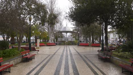 People-passing-on-a-street-in-Tavira,-Algarve-with-a-Coreto,-in-Portugal