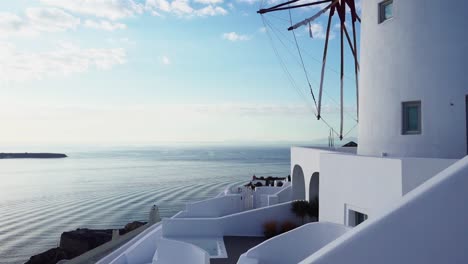 Molino-De-Viento-Blanco-En-Santorini-Con-Pequeñas-Olas-Rodando-Sobre-El-Océano-En-El-Fondo