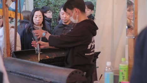 Back-view-of-chef-pouring-batter-into-mold-at-food-stand-to-make-egg-waffles