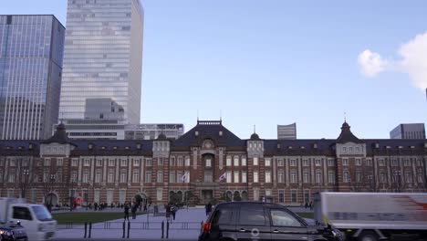 Front-View-Of-Tokyo-Station-With-Flag-Under-The-Bright-Blue-Sky-With-High-Rise-Building-In-The-Background---Wide-Shot