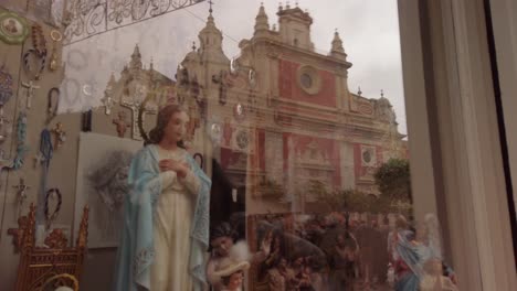 Estatua-De-La-Virgen-María-En-El-Escaparate-Con-La-Iglesia-En-La-Reflexión,-Sevilla,-España