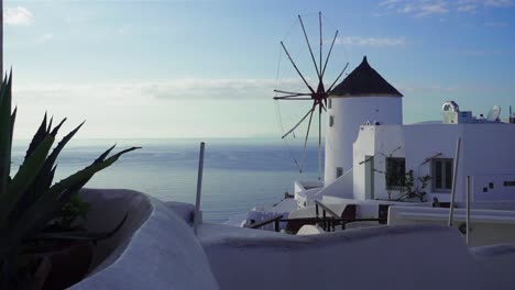 Plano-General-De-Un-Molino-De-Viento-Con-Vista-Al-Océano-Con-Un-Cactus-En-Primer-Plano,-Santorini,-Grecia