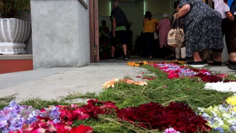 Procesión-Religiosa-Cristiana,-Cuerpo-Organizado-Cristiano-De-Personas-Que-Avanzan-De-Manera-Formal-O-Ceremonial,-El-Piso-Está-Decorado-Con-Flores-Frescas-Que-Conducen-A-La-Iglesia