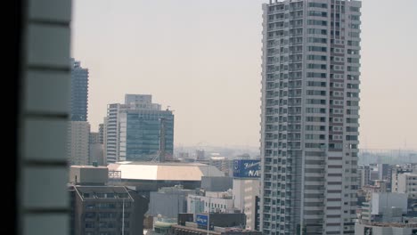 Blick-Aus-Einem-Hochhausfenster-Auf-Die-Urbanen-Strukturen-Der-Stadt,-Stabile-Handaufnahme