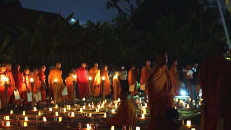 Plano-Exterior-Medio-De-Muchos-Monjes-Caminando-En-Fila-Con-Muchas-Velas-Encendidas