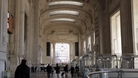 Milan-main-railway-station-building-during-daytime-with-people-walking,-wide-handheld-shot