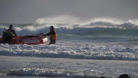 Salvavidas-De-Surf---Dos-Socorristas-Con-Chaleco-Salvavidas-Conquistando-Las-Olas-ásperas-Mientras-Tiran-Del-Bote-De-Rescate---Currumbin,-Costa-Dorada,-Australia