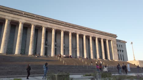 Panning-shot-of-the-University-of-Buenos-Aires-law-school,-with-people-walking-around,-during-the-morning-with-a-clear-blue-sky