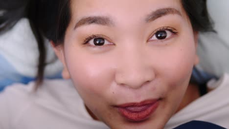 Closeup-of-Female-Smiling-and-Looking-at-Camera-and-lovely-Lies-in-Bed-Covered-with-Blanket