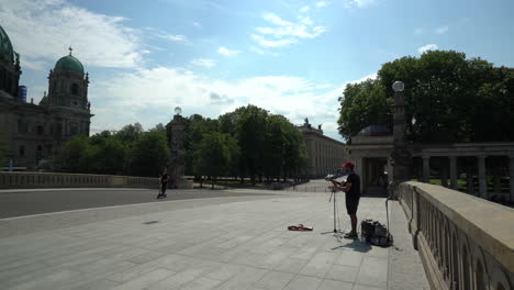 Ejecutante-De-La-Calle-Tocando-La-Guitarra-En-El-Puente-De-Friedrichs-Con-La-Catedral-De-Berlín-En-Segundo-Plano-En-Berlín,-Alemania