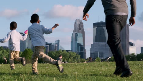 Los-Niños-Juegan-En-El-Parque-Con-El-Horizonte-De-Minneapolis-En-Segundo-Plano