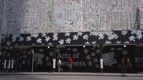 Gente-Caminando-En-Una-Acera-En-El-Distrito-Comercial-Del-Centro-De-Sydney-Cbd-Con-El-Acto-De-Amabilidad-Escribiendo-Con-Un-Mapa-Del-Arte-Del-Edificio-De-La-Ciudad-De-Sydney-Encima-De-Ellos