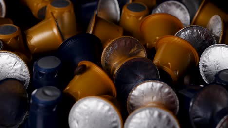 Coffee-beans-fall-onto-assortment-of-coffee-capsules-on-table