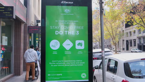 Group-walking-past-Stay-Covid-Free-government-advertisement