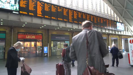 El-Hombre-Está-Parado-Revisando-Los-Horarios-De-Los-Trenes-En-La-Estación-De-Kings-Cross-Durante-La-Pandemia-De-Coronavirus-En-Londres,-Reino-Unido