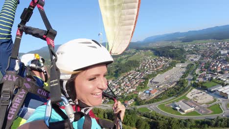 Pareja-Feliz-Disfruta-De-Parapente-En-Tándem-Sobre-Un-Campo-Exuberante,-Slovenj-Gradec