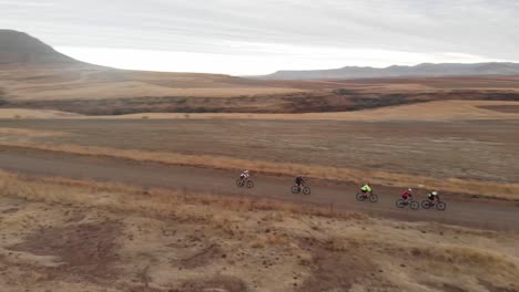 Toma-Aérea-Giratoria-De-Ciclistas-De-Montaña-En-Un-Camino-De-Grava.