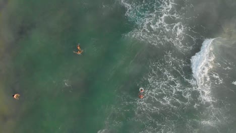 Vista-Aérea-Giratoria-De-Arriba-Hacia-Abajo-De-Los-Turistas-Emocionados,-Disfrutando-Y-Jugando-Con-Las-Olas-En-Medio-Del-Mar