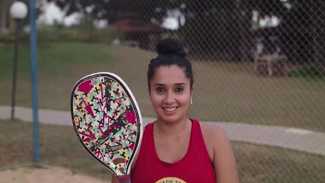 Retrato-De-Una-Joven-Sonriendo-Y-Escondiéndose-Detrás-De-Una-Raqueta-De-Tenis-De-Playa-Durante-Las-Vacaciones