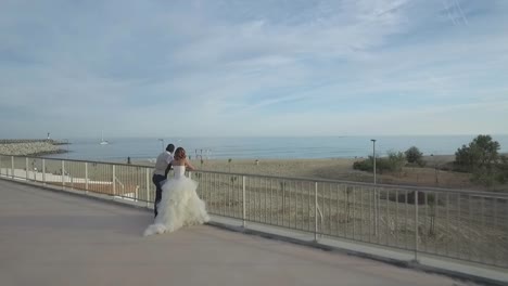 Volando-Sobre-La-Novia-Y-El-Novio-Románticos-Con-Vistas-A-La-Playa-Y-Al-Mar,-Antena