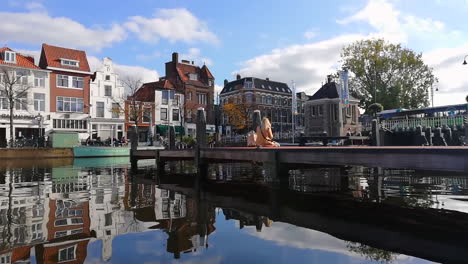 Tiro-De-ángulo-Bajo-Del-Río-Leiden,-Niña-Sentada-En-El-Puente-Durante-El-Hermoso-Día-De-Verano-En-Países-Bajos