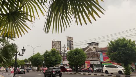 Ajetreado-Tráfico-Diario-En-La-Ciudad-De-Yogyakarta,-Isla-De-Java,-Indonesia,-Tiendas-Y-Automóviles-Bajo-Un-Cielo-Nublado-Durante-La-Temporada-De-Lluvias