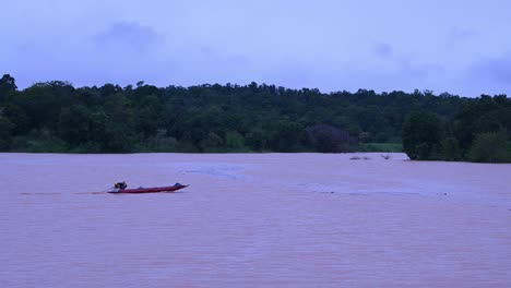 Fisherman-navigating-a-flooded-lake-speeding-towards-the-right-side-of-the-frame-and-then-turns-to-the-left-as-captured-in-Wangnamkeaw,-Nakhon-Ratchasima,-Thailand