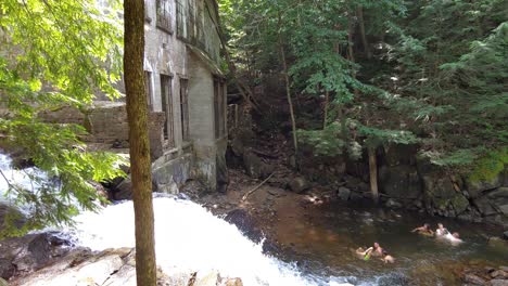 People-bathing-next-to-a-small-waterfall,-Quebec,-Canada,-wide-shot-panning-right