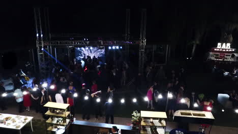 Toma-Aérea-De-Una-Fiesta-De-Bodas-Al-Aire-Libre-En-Un-Gran-Escenario-Por-La-Noche