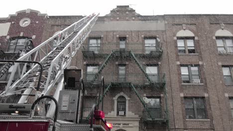 Escalera-De-Bomberos-Que-Llega-A-La-Azotea-De-Brooklyn-Supervisada-Por-Bomberos-Bajo-Nevadas---Amplio-Tiro-Inclinado-Hacia-Arriba