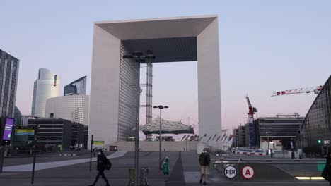 Gran-Arco-De-La-Defense-Y-Entrada-Del-Metro-Con-Pocas-Personas-Caminando-Durante-Las-Primeras-Horas-De-La-Mañana-En-Invierno.