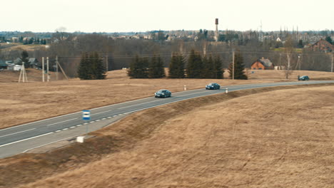 Imágenes-De-Drones-De-Autos-Eléctricos-Porsche-Taycan-Conduciendo-En-Una-Carretera-Rural,-Lituania