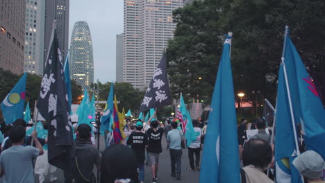 Crowd-Of-Rallyists-Waving-Flags-While-Walking-In-The-Street-In-Tokyo,-Japan