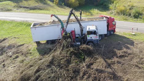 Wood-chipper-blowing-shredded-wood-into-back-of-truck-in-Sentrupert,-Slovenia