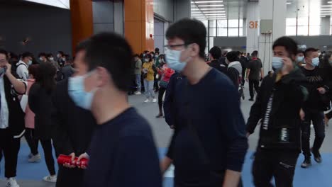 People-wearing-masks-and-walking,-looking-around-in-between-product-pavilions-at-kitchen-design-exhibition-in-China,-during-COVID-19-Pandemic