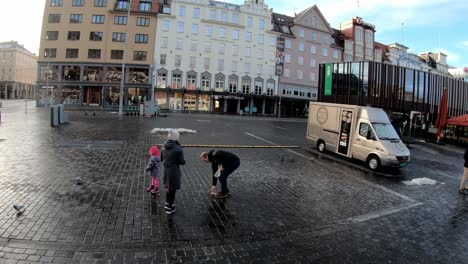 Family-with-cute-little-girl-feeding-birds-in-city-of-Bergen