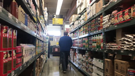 Un-Comprador-De-Hombre-Con-Carrito-De-Empuje-Caminando-Por-El-Pasillo-De-La-Tienda-De-Comestibles-En-El-Almacén-Inteligente-De-Servicio-De-Alimentos-En-Coos-Bay,-Oregon