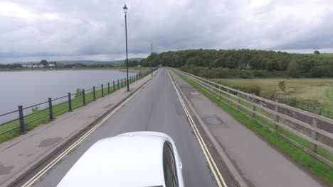 Conduciendo-Un-Coche-A-Lo-Largo-Del-Lago-En-El-Campo-En-Inglaterra