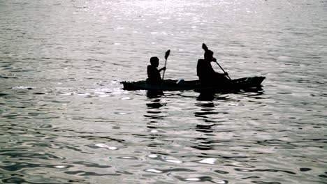 Two-skilled-people-kayaking-in-the-sea-at-sunset-in-Praia-da-Sepultura,-Brazil