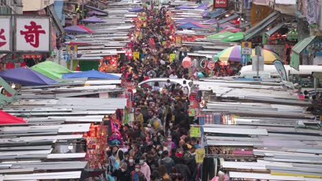 Large-crowds,-hundreds-of-shoppers,-walk-through-the-Fa-Yuen-street-market-stalls-as-they-look-for-bargain-priced-vegetables,-fruits,-gifts,-and-fashion-goods-in-Hong-Kong