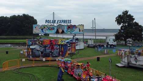 Empty-overcast-British-amusement-park-aerial-view-deserted-funfair-rides-low-angle-forward-shot