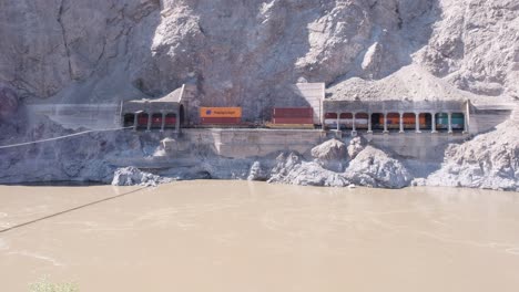 Der-Schlammige-Fluss-Wirbelt-Vor-Uns,-Während-Der-Güterzug-Durch-Tunnel-Fährt