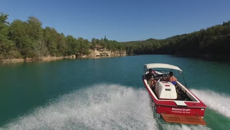 Siguiendo-La-Lancha-Rápida-De-Esquí-De-La-Embarcación-Maestra-Roja-A-Través-De-La-Laguna-Del-Lago-Azul-Brillante-Acelerando-El-Disparo-De-Un-Dron