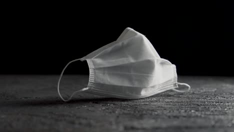 Face-mask-in-white-on-a-table-with-black-background-filmed-on-a-slider