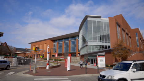 Modern-Exterior-Of-North-Carolina-State-University-In-Raleigh,-NC-With-People-Walking-And-Cars-Parked-Outside-The-Building