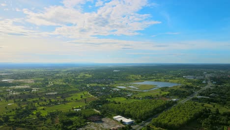 Vista-Aérea-Moviéndose-Y-Viendo-El-Campo-Pantanoso-Con-La-Carretera-Un-Día-Soleado-En-Khonkaen,-Tailandia