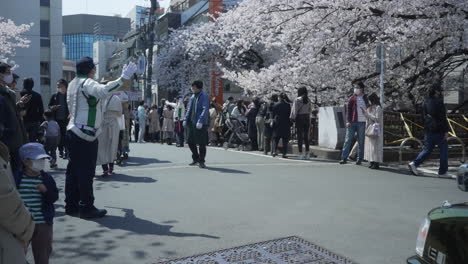 Oficial-De-Tráfico-Dirigiendo-En-La-Calle-Con-Muchas-Personas-Durante-El-Evento-Hanami-En-La-Ciudad-De-Tokio,-Japón