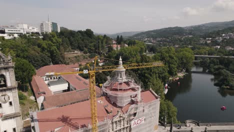 Edificio-Histórico-En-Construcción-Con-Alta-Grúa-Industrial-En-La-Costa-Del-Río,-Vista-Aérea