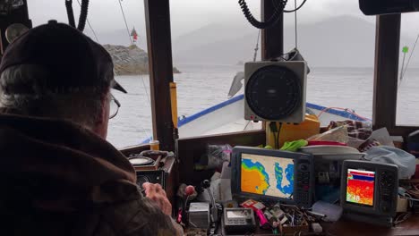 A-retired-fisherman-navigates-his-boat-out-of-an-Alaskan-harbor-on-an-overcast-day