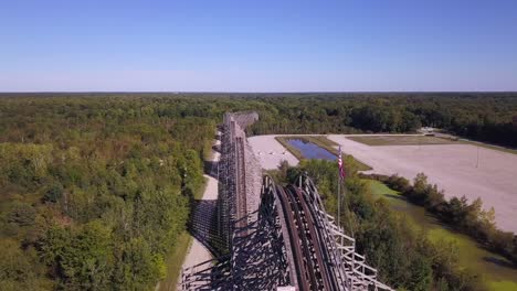 Panorámica-Aérea-De-Montaña-Rusa-Con-Bandera-Americana-Por-Bosque,-Michigan